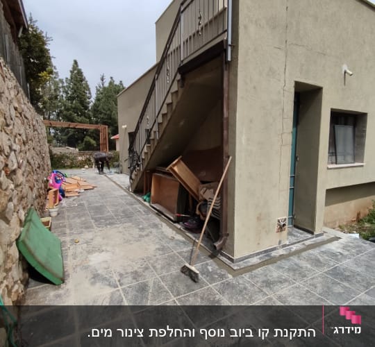 אדם עובד בחוץ ליד בית עם כלים שונים